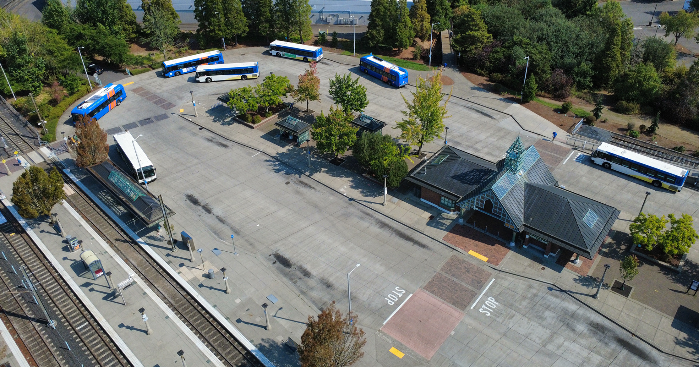 Buses waiting at stops, light rail on the left, shelters in the middle at Beaverton Transit Center.